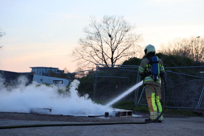 Brandweer blust brandende pallets