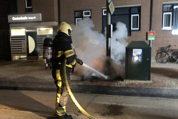Houtstapel in brand naast container