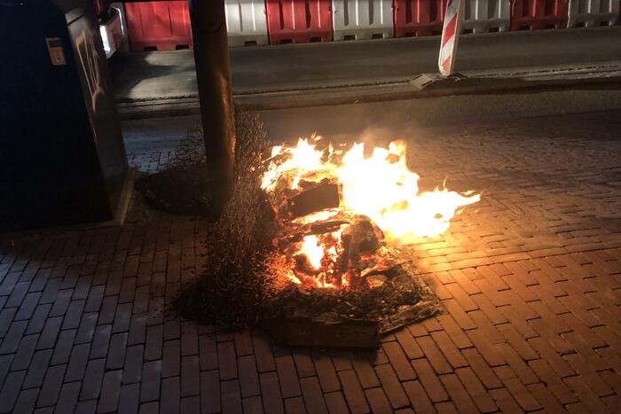Houtstapel in brand naast container