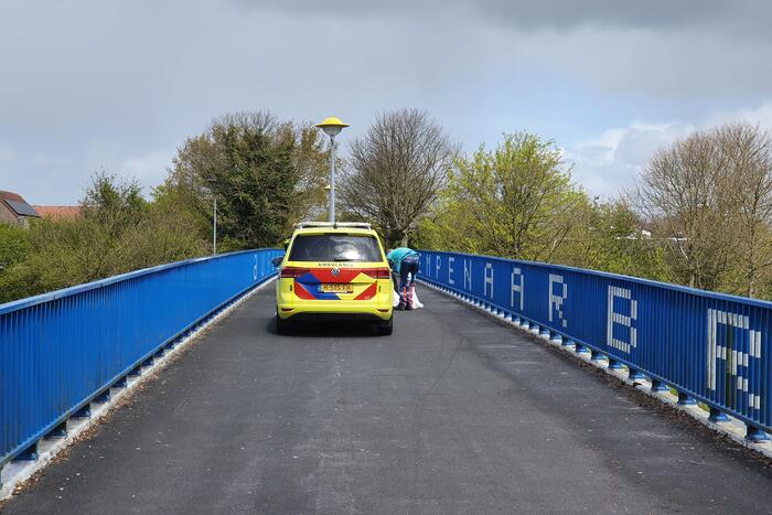 Man en vrouw gaan met scooter onderuit op fietsbrug