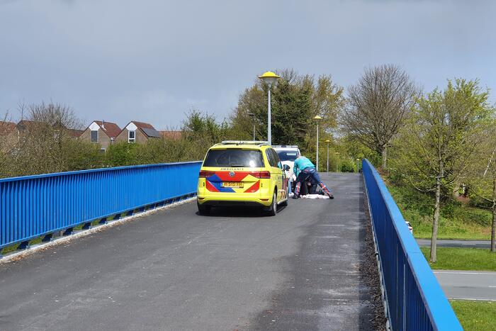 Man en vrouw gaan met scooter onderuit op fietsbrug