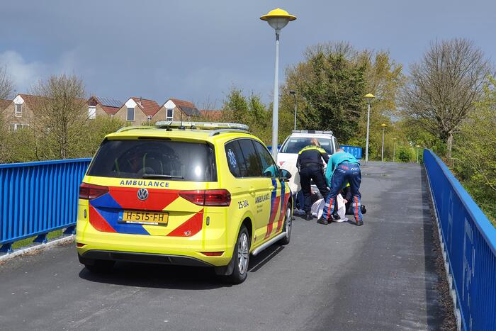 Man en vrouw gaan met scooter onderuit op fietsbrug