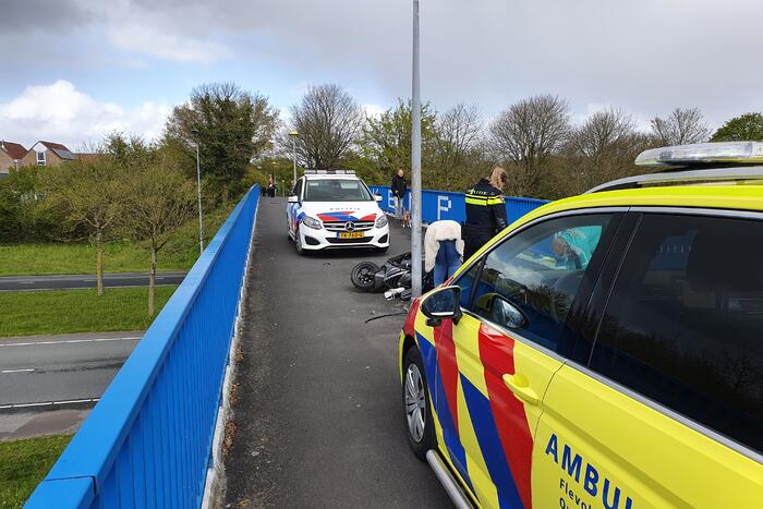 Man en vrouw gaan met scooter onderuit op fietsbrug