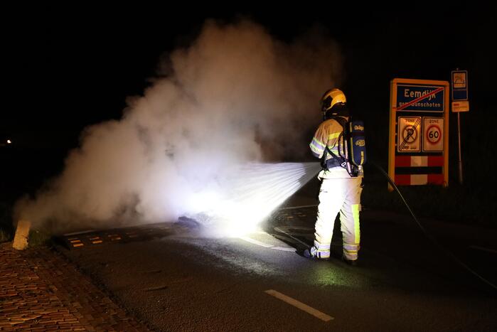 Brandweer blust brandende band op midden van weg