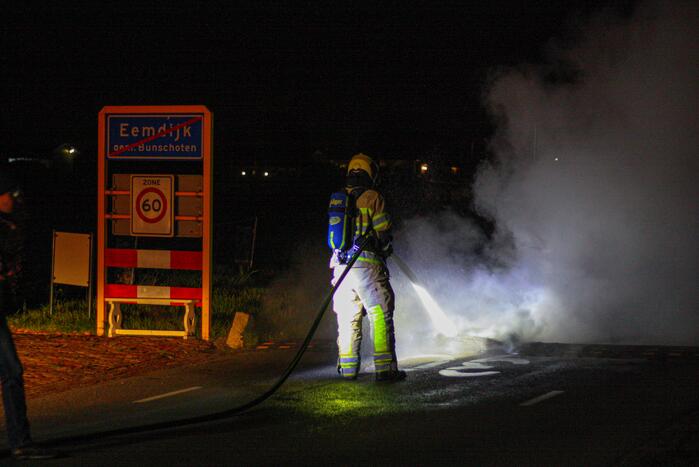 Brandweer blust brandende band op midden van weg