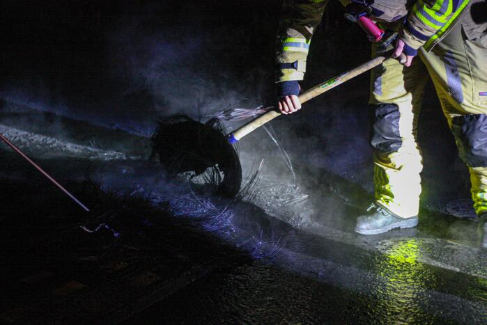 Brandweer blust brandende band op midden van weg