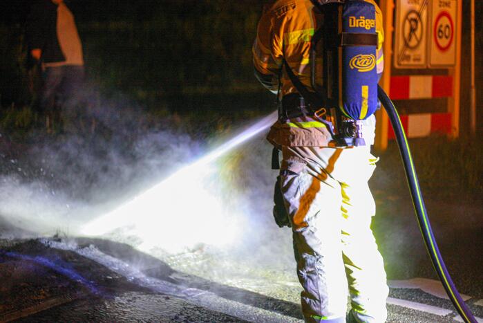 Brandweer blust brandende band op midden van weg