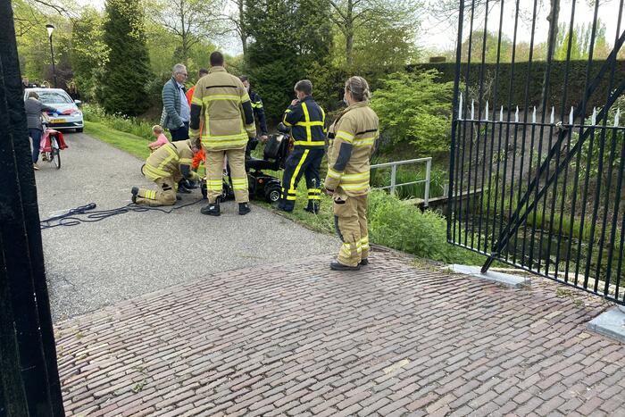 Persoon rijdt met scootmobiel het water in