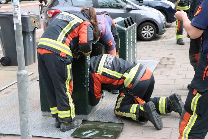 Brandweerman kruipt in ondergrondse papiercontainer voor verloren horloge