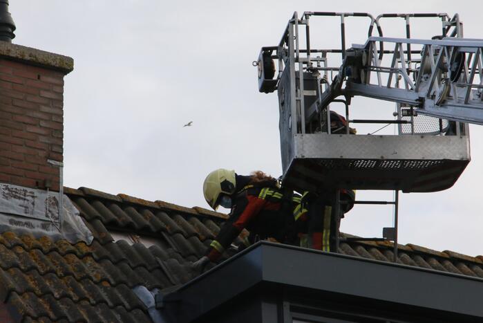 Brandweer legt weggewaaide dakpannen terug