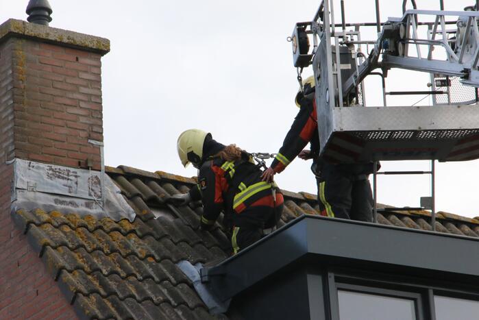 Brandweer legt weggewaaide dakpannen terug