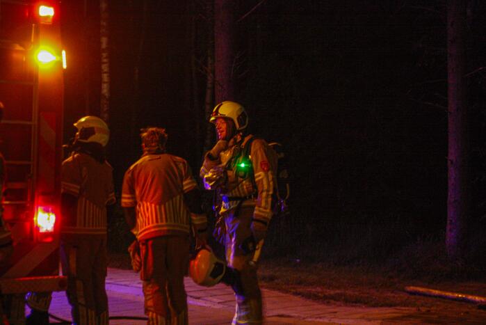 Brandweer blust brandende stukken hout