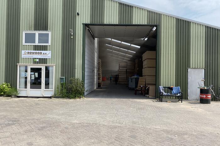 Brandweer blust brandende container met houtpulp bij houtbedrijf Rowood