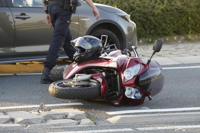 Personenauto en motor botsen op rotonde