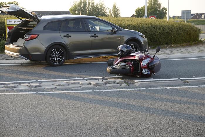 Personenauto en motor botsen op rotonde