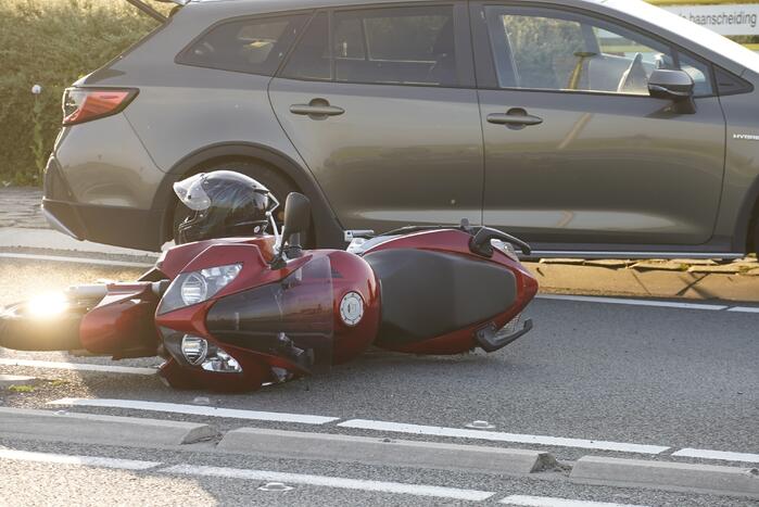 Personenauto en motor botsen op rotonde
