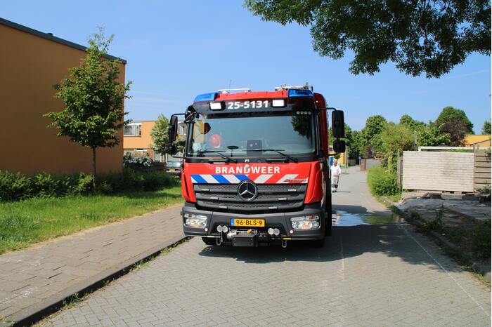 Brandweer blust in brand staande schutting
