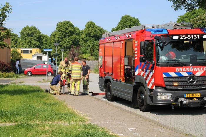 Brandweer blust in brand staande schutting