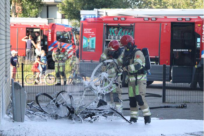 Brandweer blust brandende stapel fietsen