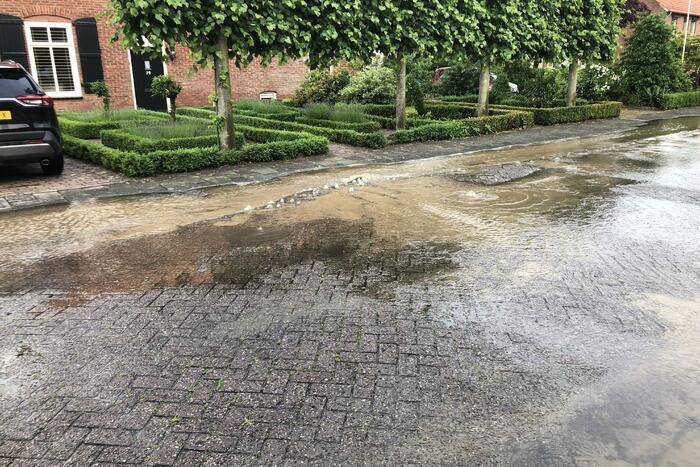 Straat onder water door gesprongen waterleiding