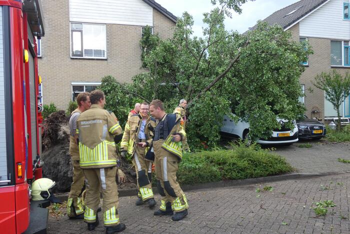 Boom waait om tegen woning en auto