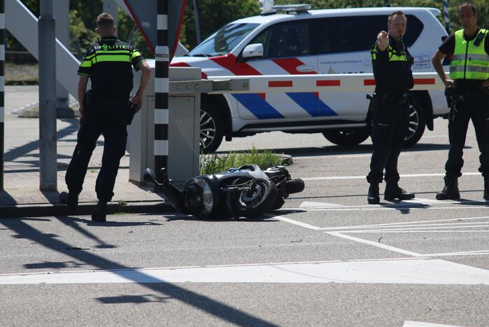 Auto botst op scooter voor ingang veerdienst