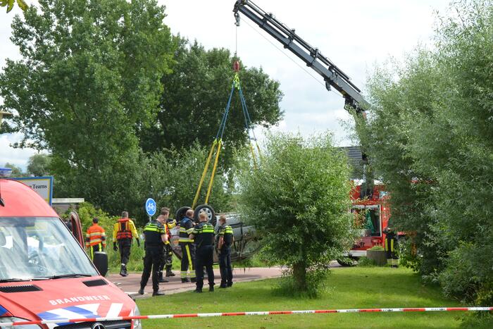 Auto schiet van de weg en belandt ondersteboven in het water