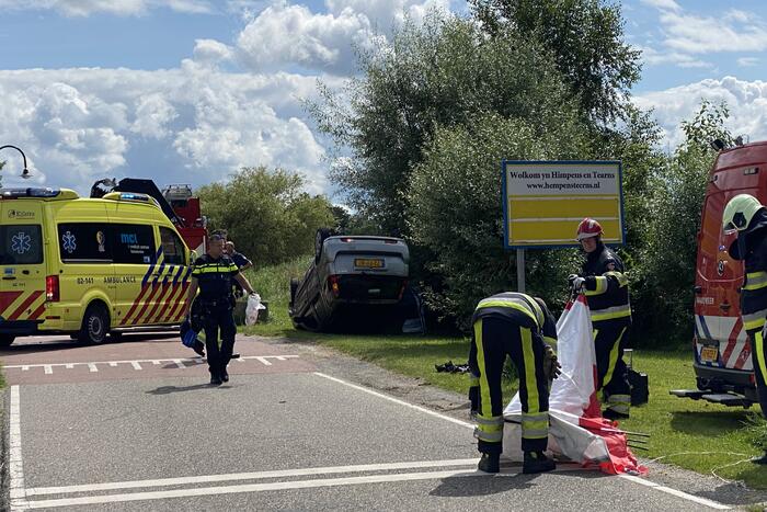 Auto schiet van de weg en belandt ondersteboven in het water