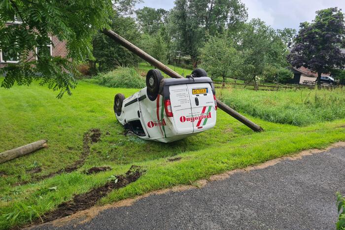 Bezorgauto slaat over de kop en ramt stroommast