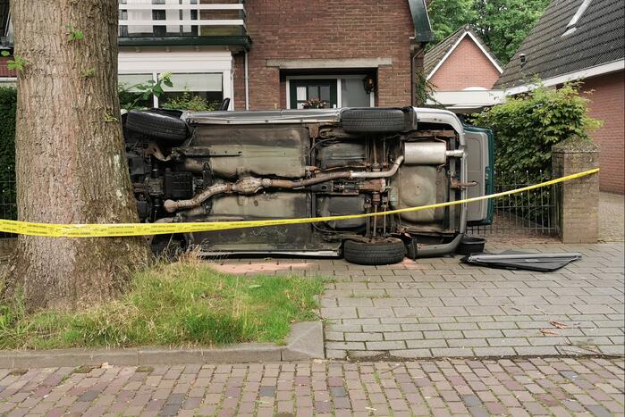 Auto belandt op zijn kant tegen hekwerk