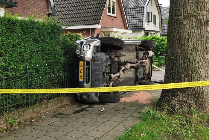 Auto belandt op zijn kant tegen hekwerk