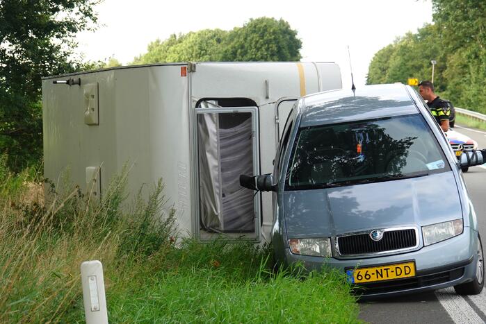 Auto met caravan belandt op zijn kant