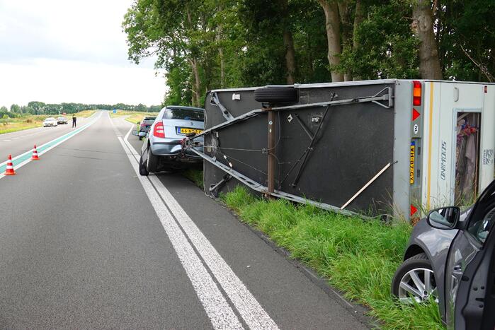 Auto met caravan belandt op zijn kant