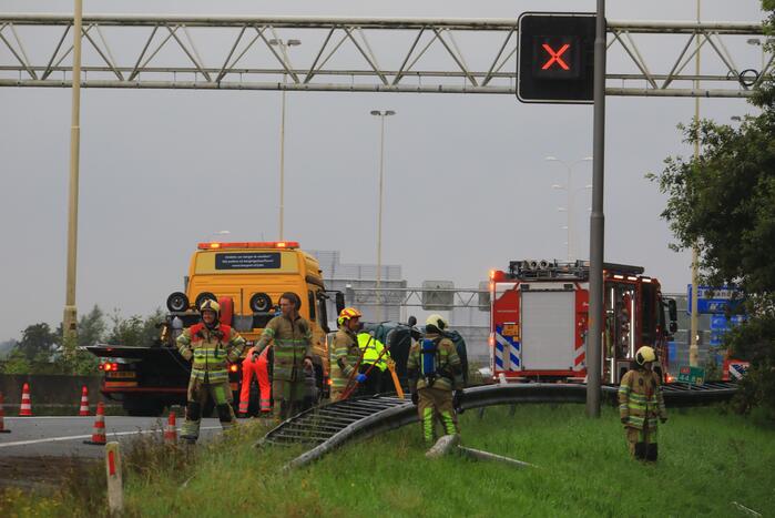 Auto glijdt over vangrail heen en belandt op zijn kop