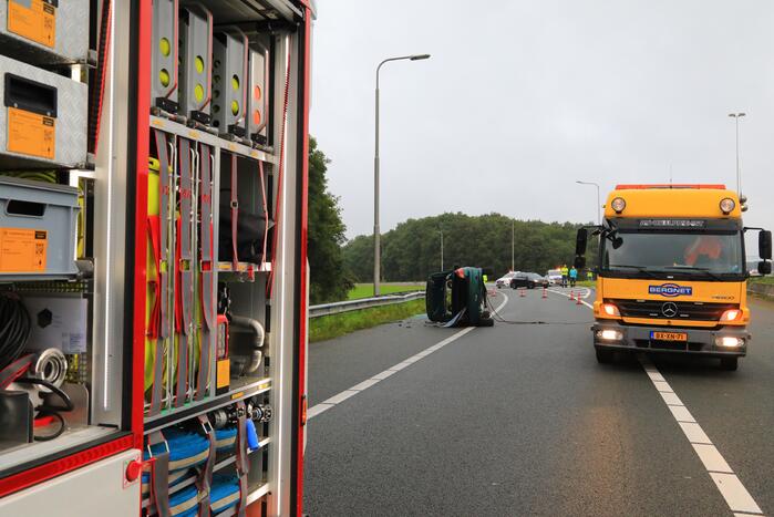 Auto glijdt over vangrail heen en belandt op zijn kop