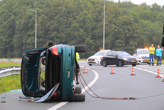 Auto glijdt over vangrail heen en belandt op zijn kop