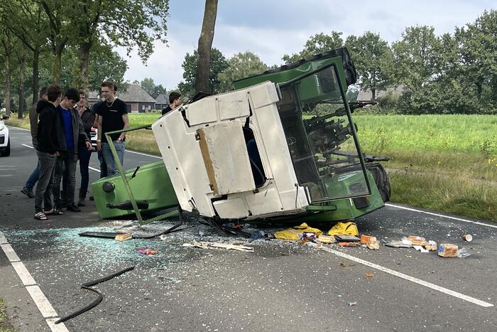 Tractor over de kop na botsing met boom