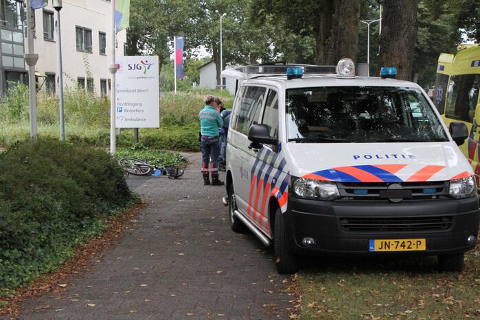 Vrouw met fiets gaat onderuit voor ingang ziekenhuis