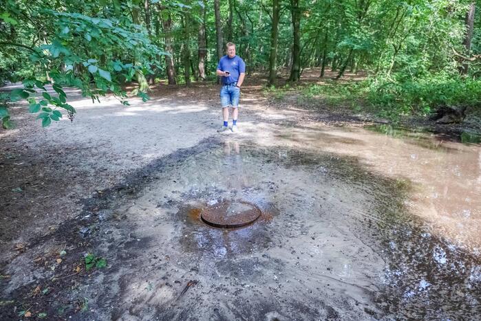 Putdeksel komt omhoog en zorgt voor wateroverlast op bospad