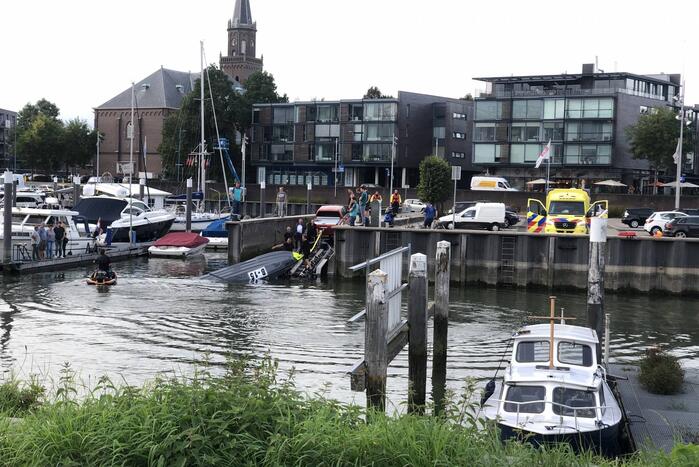 Omgeslagen boot wordt opgetakeld in jachthaven
