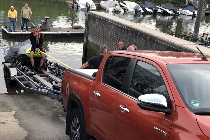 Omgeslagen boot wordt opgetakeld in jachthaven