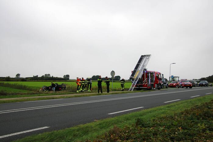 Auto raakt na botsing van de weg en belandt op de kop in weiland
