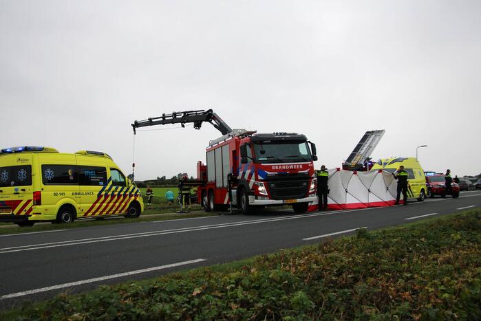 Auto raakt na botsing van de weg en belandt op de kop in weiland