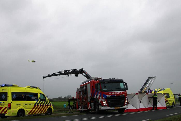 Auto raakt na botsing van de weg en belandt op de kop in weiland