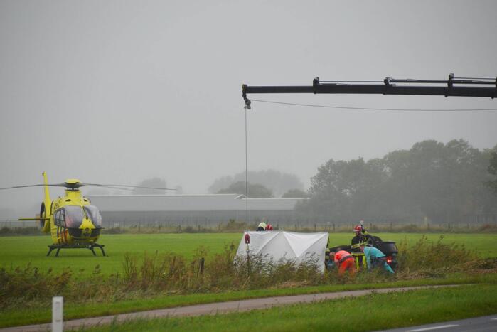 Auto raakt na botsing van de weg en belandt op de kop in weiland
