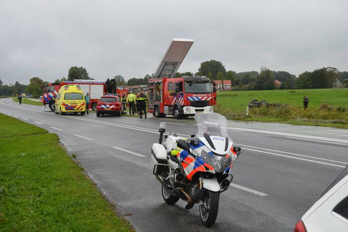 Auto raakt na botsing van de weg en belandt op de kop in weiland