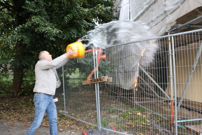 Omstanders blussen brand op bouwplaats