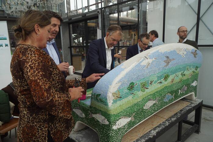 Burgemeester Röell helpt bij beplakken Social Sofa bij woonwarenhuis Nijhof