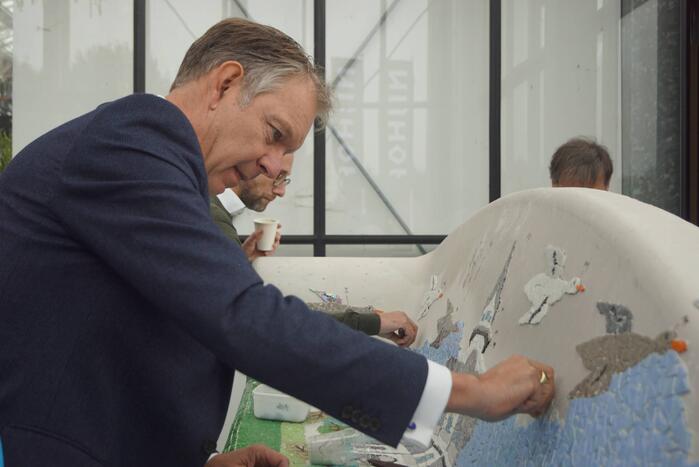 Burgemeester Röell helpt bij beplakken Social Sofa bij woonwarenhuis Nijhof