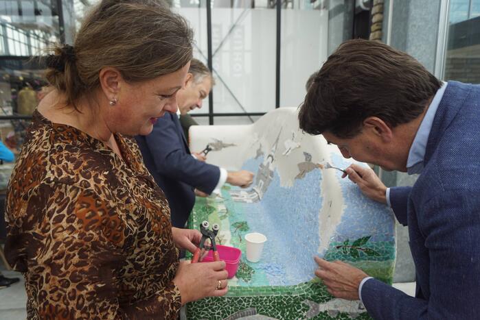 Burgemeester Röell helpt bij beplakken Social Sofa bij woonwarenhuis Nijhof